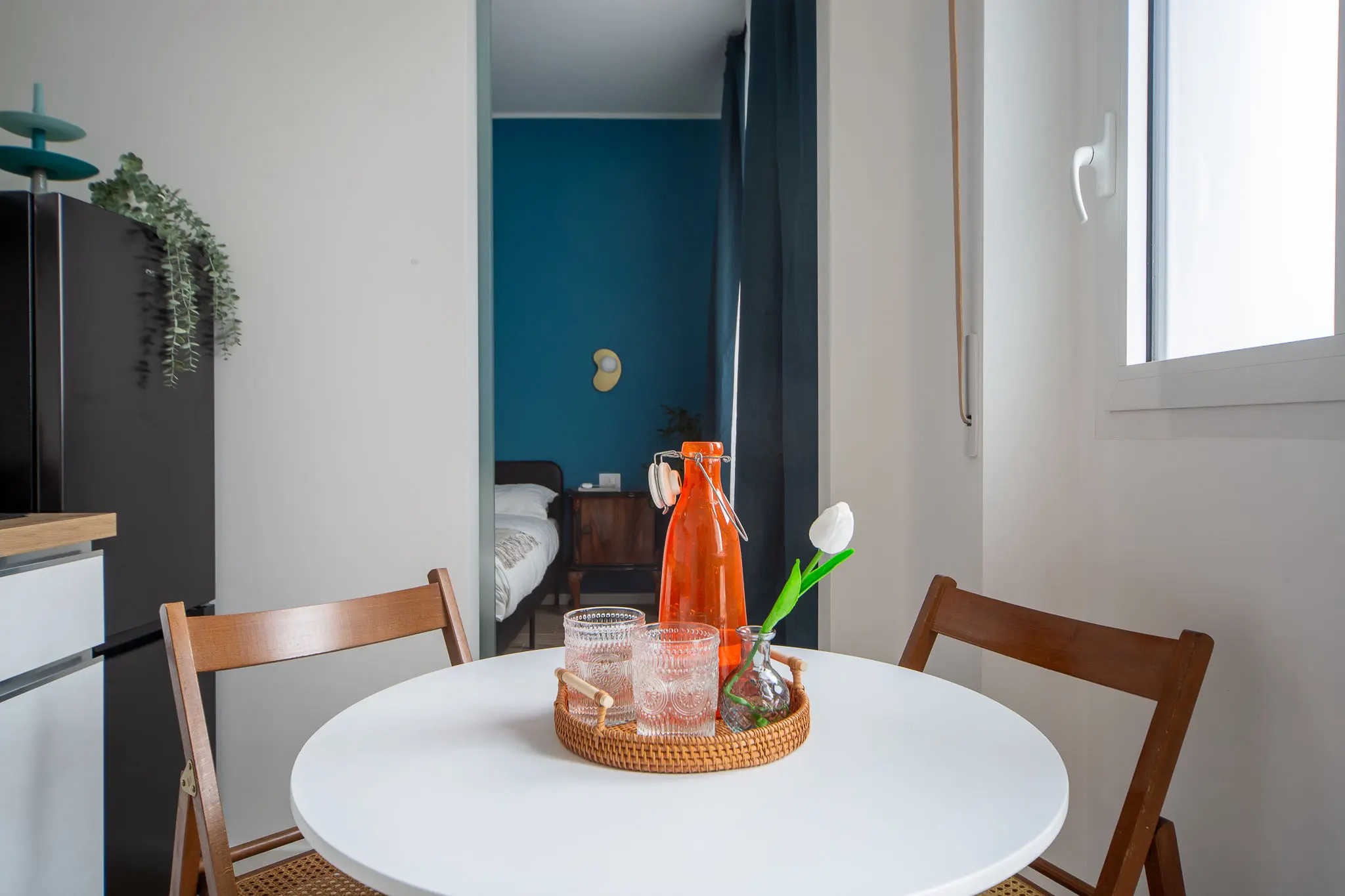 home-styling-di-cucina-con-il-tavolo-rotondo-e-sedie-vintage-in-fondo-quadretti-fornasetti